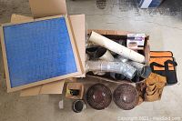 Various construction items including metal pipes, two brown concentric gas vents, blower motor, tool bag and tool belt captured from overhead.