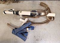 Photo of the bazooka style gold dredge showing the main metal tube with attached hoses and blue rubber hose sections.