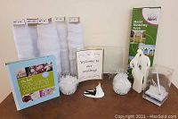 Photo shows all wedding starter kit contents arranged on a table: planner, tulle rolls, welcome sign, candle, pen holder, cake toppers, metal arch box.
