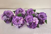 Six small artificial flower bouquets arranged in two rows on a white surface, showing their size and grouping.