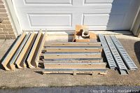 Group of polymer concrete channel sections and slot grates laid on driveway in front of garage door
