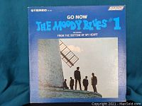 Close-up photo of the front cover of a Moody Blues vinyl record single called "Go Now." It shows band members silhouetted near a windmill and blue text on the cover.