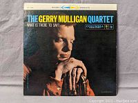 Front cover of the vinyl album 'The Gerry Mulligan Quartet - What Is There To Say?' showing a color photo of Gerry Mulligan with a baritone saxophone and the Columbia label.