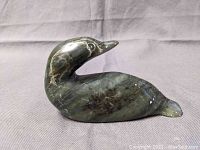 Front angle view of the signed Inuit soapstone bird carving showing the smooth surface, colors, and etched eye detail.