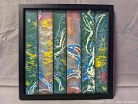 Framed mixed media artwork with vertical strips featuring swirling abstract patterns in green, yellow, blue, white and copper hues.