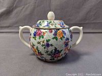 Front angled view of the porcelain sugar bowl with floral design, showing handles and lid knob