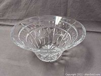 Clear Waterford crystal bowl with wide flared rim and intricate cut faceted pattern photographed from above on a gray cloth background.