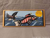 Front view of the indigenous art wood panel featuring a stylized fish and eagle against a blue background with sun.