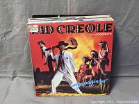 Front view of vinyl record lot showing Kid Creole and the Coconuts album on top with vibrant orange cover