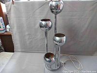 Front view of the chrome table lamp with four globes showing minor surface wear and rust.