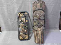 Front view of the mask and dancer plaque side by side on a white background showing overall design and scale.