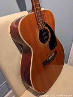 Side-angle view of guitar body showing square-shoulder dreadnought shape, binding and finish.