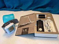 Photo showing both items: a wrist blood pressure monitor and a boxed itty bitty book light with accessories.