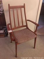 Front left angled view of wooden Mid Century Modern arm chair showing vertical back slats, curved arms, and fabric seat.