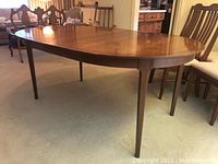 Side view of oval wooden dining table showing four tapered legs and smooth finish