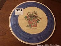 Top down view of Wedgwood ceramic cake server with blue border and potted Fragaria vesca plant in center.