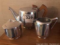 Full set of Piquoit Ware mid century tea set with teapot, creamer, and sugar bowl shown together on a wooden surface.