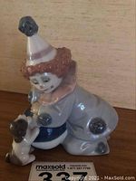 Front-side view of the clown figurine interacting with the puppy on a ball