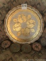 Overall view of vintage round Florentine tray with four small coasters on fabric surface