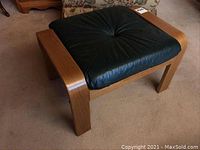 Side-angle view showing the black leather top with radial stitching and wooden bentwood frame with curved legs.