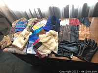 Overview of the ladies scarves and gloves arranged on a wooden surface, featuring various patterned scarves and leather gloves in multiple colors.
