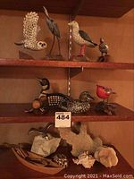 Overview of two shelves with all carved birds and coral, wooden bases, and kayak figurine
