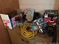 Overview of all items together on a wooden surface including sander, vacuum, polisher box and cords
