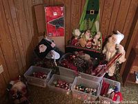 Wide view showing artificial tree, boxes with ornaments, Santa figurines, and decorative sleigh with Christmas decor