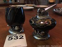 Side-by-side front view of Ronson Nordic table lighter and match holder on wood table with auction tag 532.