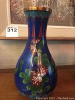 Front view of blue cloisonné vase displaying pink and white flower motifs and green leaves on deep blue enamel background