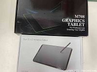 Boxes of UGEE M708 and XP-PEN Star 05 V2 Wireless graphics tablets shown together, labels and branding visible.