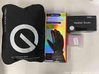 Black Venustas waterproof bag with logo, SabotHeat heated gloves box, black heated socks box, Timelife Pebble hand warmer box.