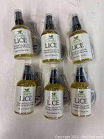 Front view of six sealed 4 oz spray bottles of Isabellas Clearly Lice Remover, each bottle labeled and including metal combs.