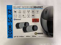 Photo of the TCOM SC X2 helmet intercom headset box showing branding, twin pack, Bluetooth, FM radio, up to 1000m range, and water resistance.