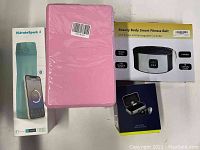 Photo showing HidrateSpark 3 water bottle in box, pink yoga blocks, Beauty Body Smart Fitness Belt box, Mifo O5 wireless earbuds box.