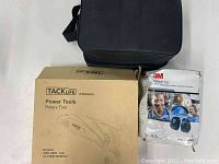 Photo showing black carrying case, Tacklife rotary tool box, 3M PELTOR Optime 101 ear muffs box.