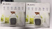 Two boxed Blaux Portable AC-G2 fans, packaging showing front view and icons