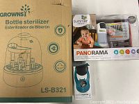 Lot items shown with original packaging: Growns bottle sterilizer LS-B321 cardboard box, Summer Infant Panorama baby monitor boxed, Toddler Monitor door alarm boxed.