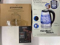 Boxes of the Stariver electric hot pot, Hamilton Beach glass kettle, and Dyna Mix culinary torch