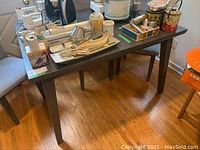 Wooden table shown with various items on top for size reference and condition, emphasizing chips and heavy wear on edges.