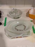 Multiple Pyrex glass dishes stacked, showing divided dish, casserole dishes, and lids