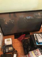 Large 50-inch LG flat screen television on floor with telephone and cables nearby