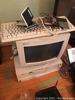 Compaq Deskpro computer tower with HP keyboard on top and HP CRT monitor behind, battery tester and calculator next to it