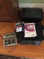 Epson Stylus Colour 660 printer, user manual, Epson 220 ink cartridge box, Sharp adding machine, and HP Deskjet F4435 printer arranged on floor.