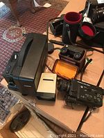 View of the lot with Chinon projector front and center, Sankyo movie camera, along with Vicko slide viewer and Orinox binocular camera in cases showing equipment and cases.