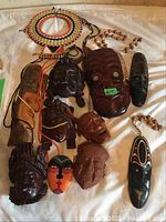 View of all nine wood and clay masks arranged on cloth.