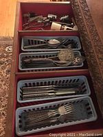 Drawer with four plastic trays holding various types of metal cutlery.