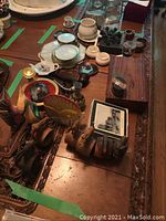 Wide shot of table showing various wooden animal napkin holders, ceramic cups, coasters, pipes, and other decor items.
