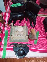 Two black carved elephant bookends and several decorative wooden figurines including a white domed architectural model, a wishing well, and a small wooden sculpture on a red and white cloth.