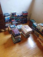 Multiple stacks of tied books in a corner of a room, showing large quantities of hardcover and paperback books.